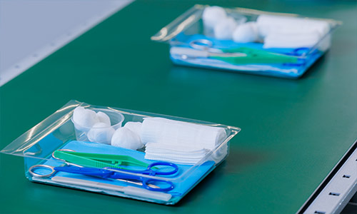 Sealed surgical pack trays moving along a production line