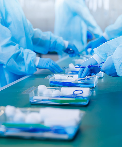 Gloved hands assembling custom surgical pack trays on a production line